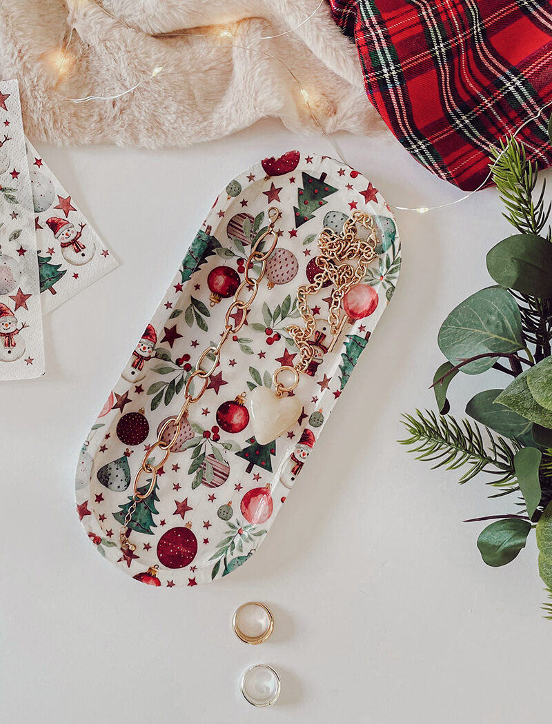 Plateau rectangulaire décoré d’une serviette de Noël, utilisé comme vide-poche avec des bijoux posés dessus.