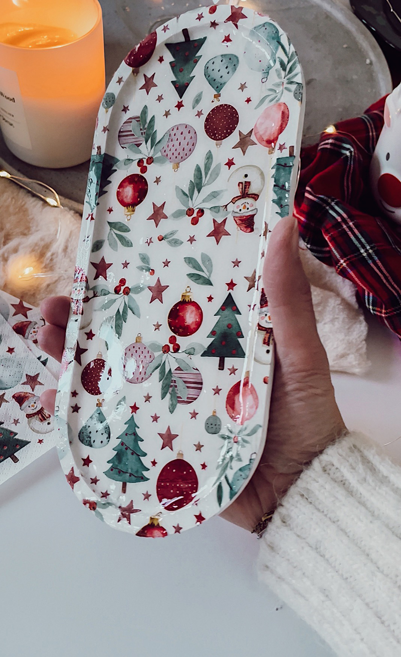 Plateau décoré de motifs de Noël, tenu en main et recouvert d’un fini brillant.