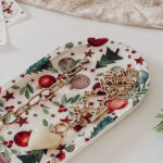 Plateau allongé décoré d’une serviette imprimée de motifs de Noël, entouré d’accessoires décoratifs.