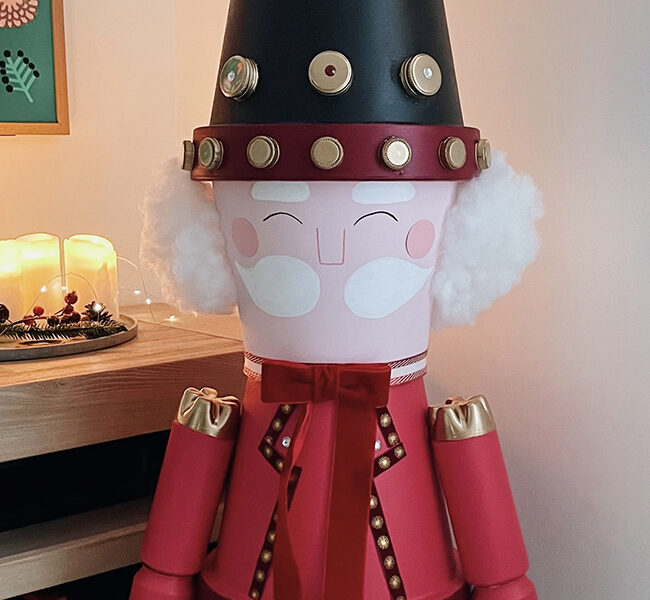 Détail du visage et du chapeau du casse-noisette géant fait maison, décoration de Noël artisanale.